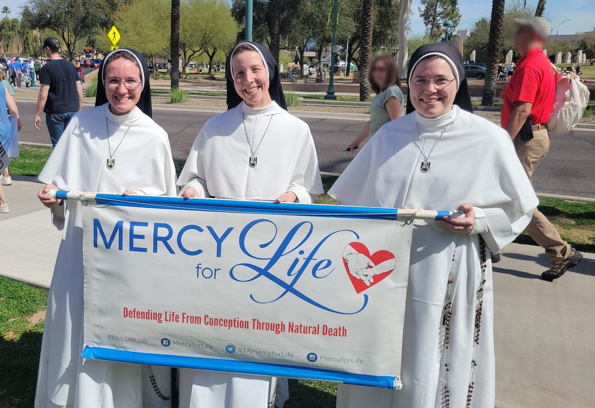 Three smiling religious sisters holding the Mercy for Life banner at the 2026 Arizona March for Life